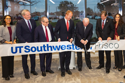 Group of people cutting a large ribbon