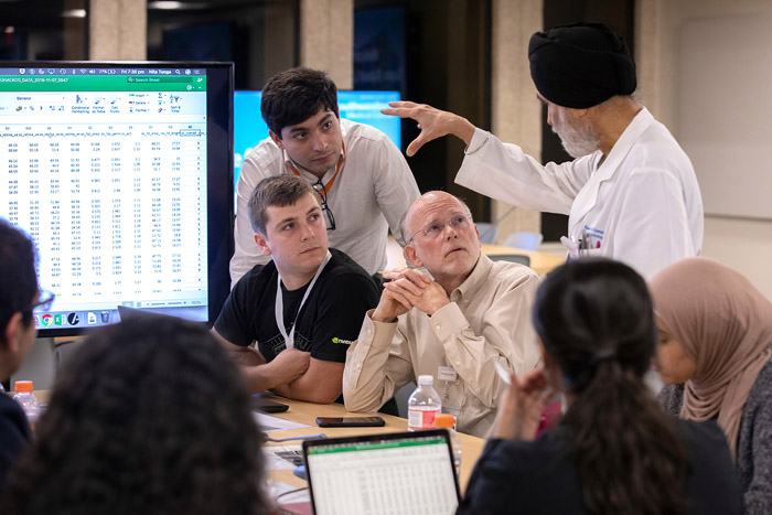 Group of people gathered around a table with a screen at the end