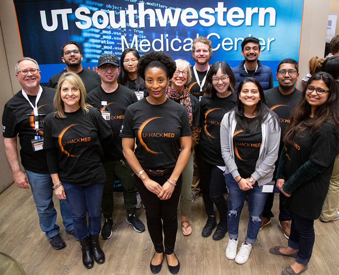 Thirteen people standing together, wearing matching shirts