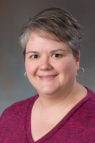 Woman with short grey hair, weraing a red top