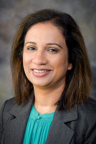 Woman with dark hair, dark jacket, green shirt