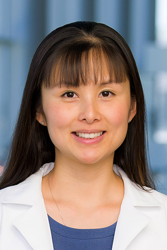 Woman with dark hair, wearing a lab coat