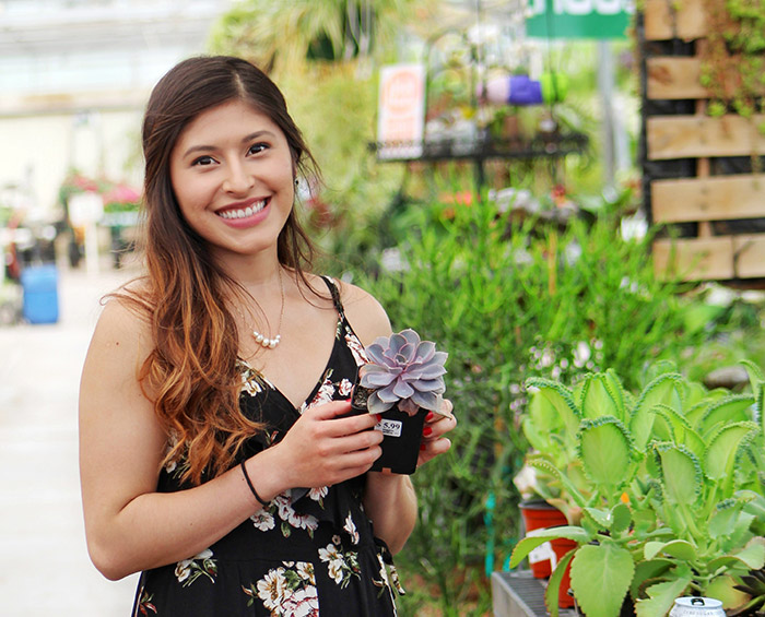 Woman holding a succulent surrounded by plants