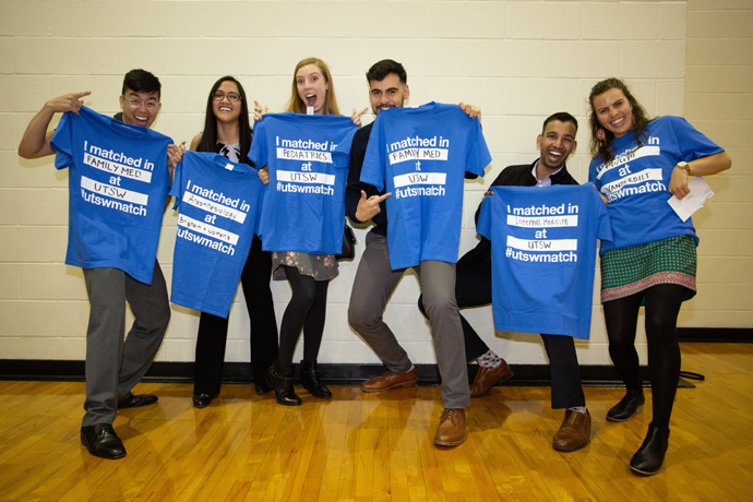 UTSW students holding t-shirts at match day