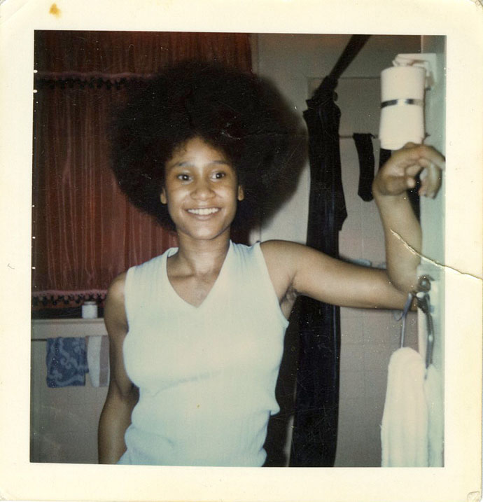 Older photograph of a young woman with an afro in a sleeveless shirt.