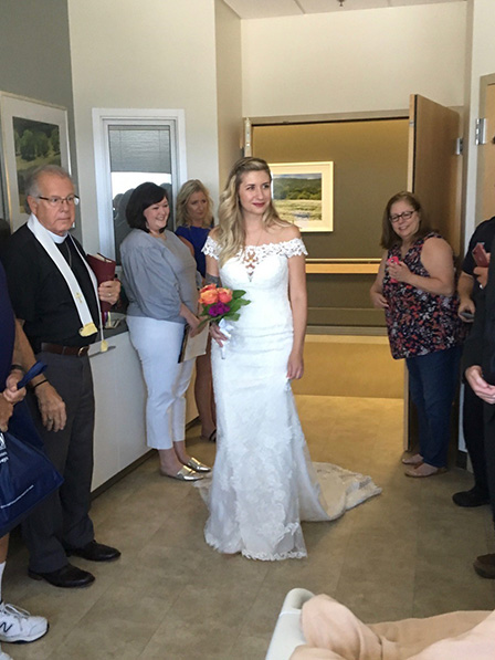 Micaela in wedding dress as staff and family look on