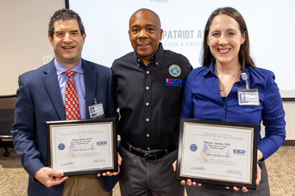 Three people, two on the sides holding a certificate award