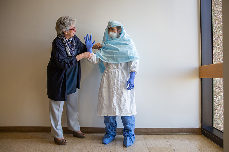 Dr. Perl adjusting protective suit on healthcare worker