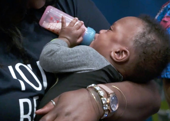 Baby drinking from bottle while held by mother