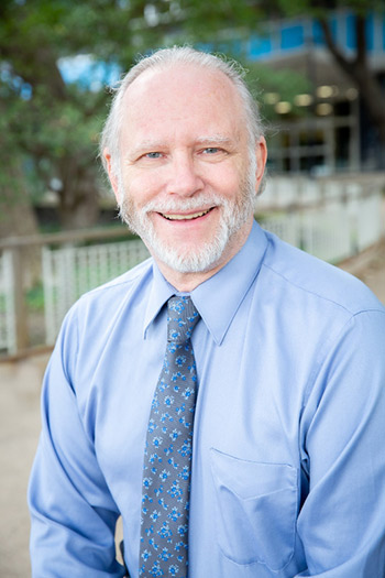 Man with gray beard, light blue dress shirt, and tie