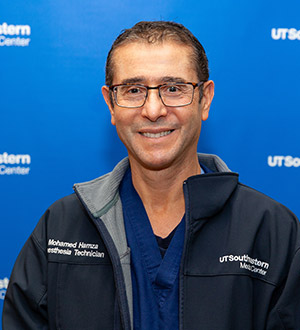 Man with glasses, dark hair, wearing a UTSW jacket