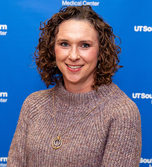 Woman with curly brown hair and a gray sweater
