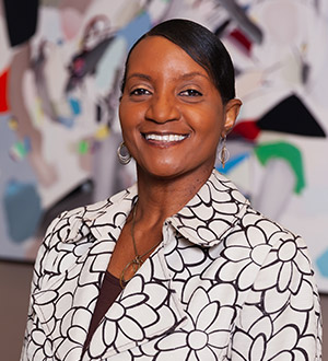 Woman with black hair and wearing a black and white flower printed blazer