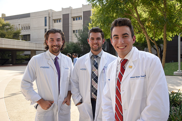 Three young men in white lab coats
