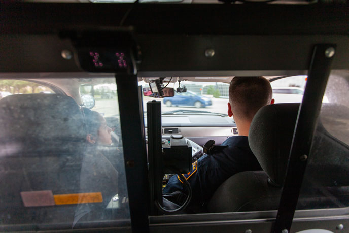 View from the back of a patrol car, two police officers sitting up front