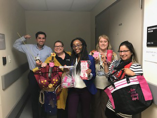 Group of five people holding a bra decorated with Wonder Woman visuals