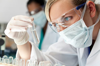 Woman in PPE looking at test tube