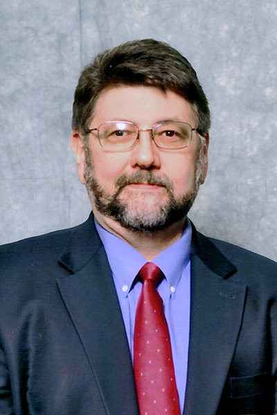 Bearded man wearing navy suit and red tie