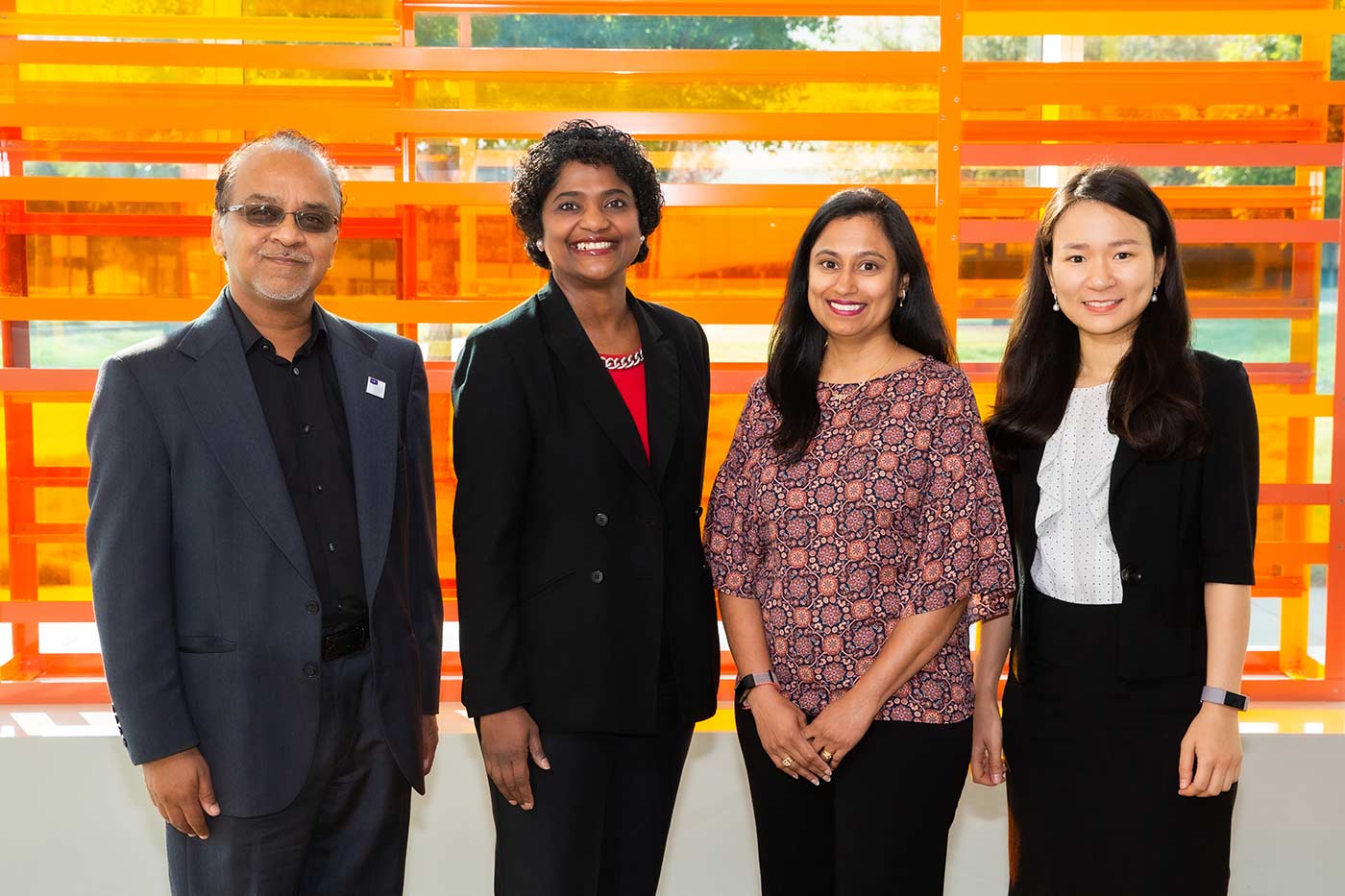 Four people standing in front of orange art