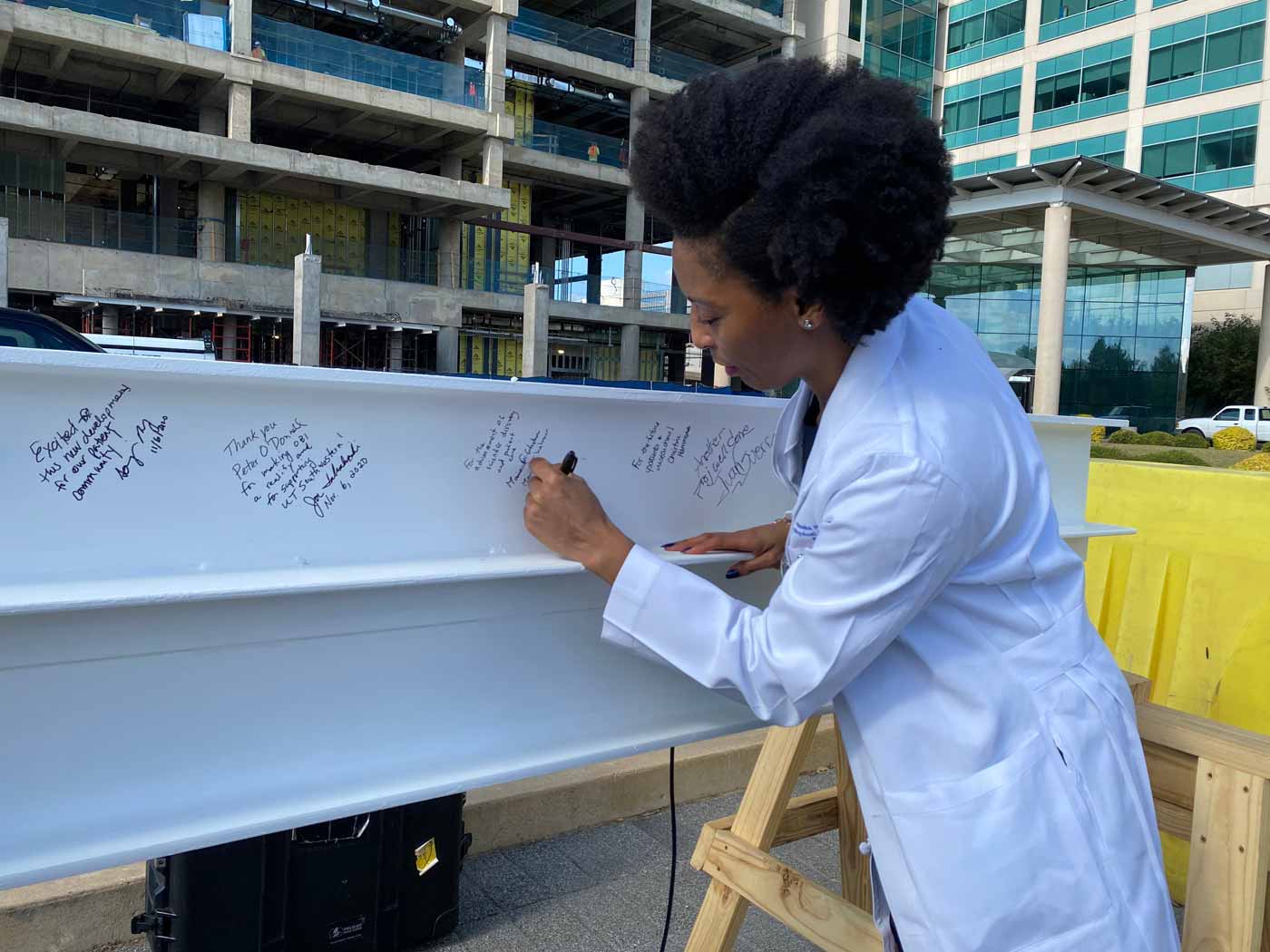 Woman in lab coat signing beam