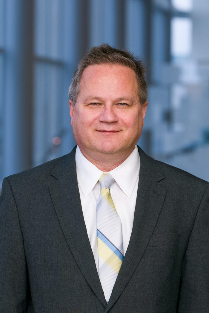 Man with light brown hair, wearing dark grey suit