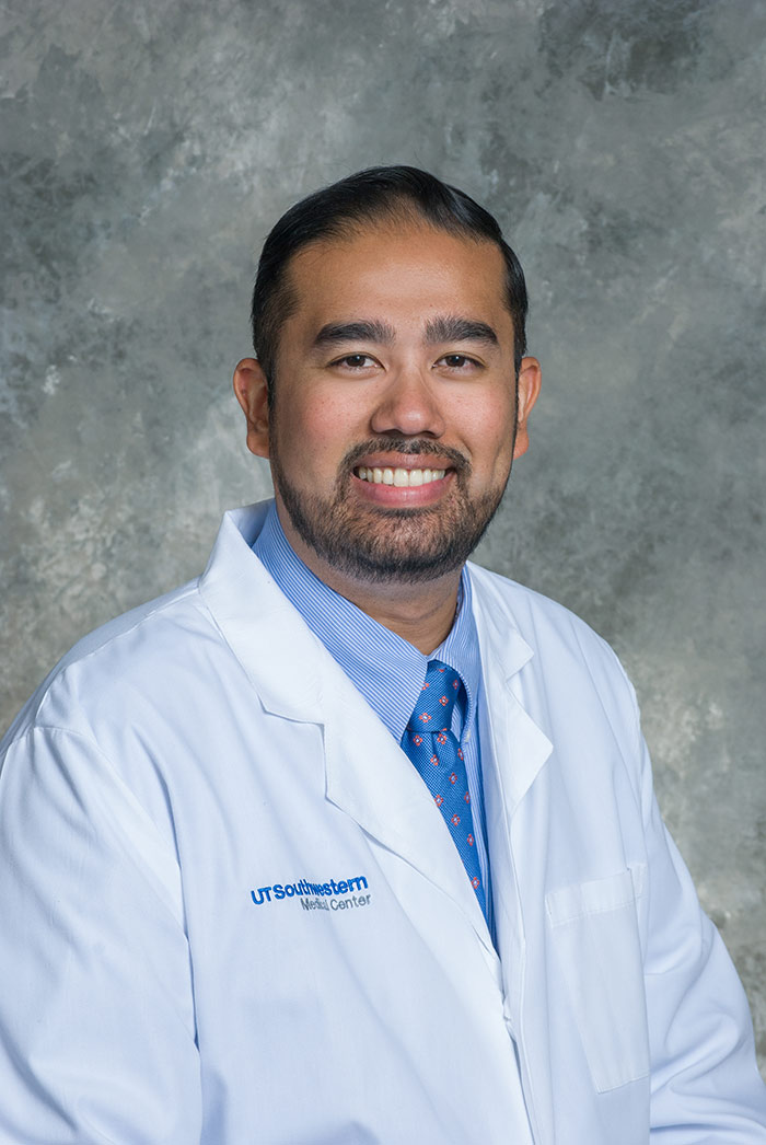 Man with short beard, dark hair, wearing white lab coat