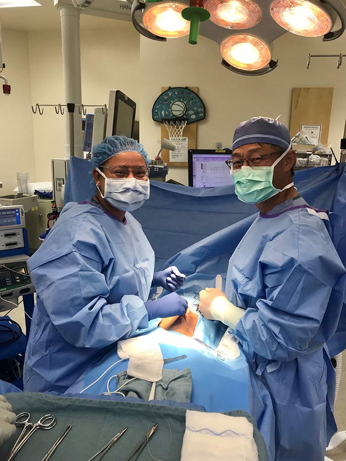 Two people in surgical scrubs and masks in a surgery room.