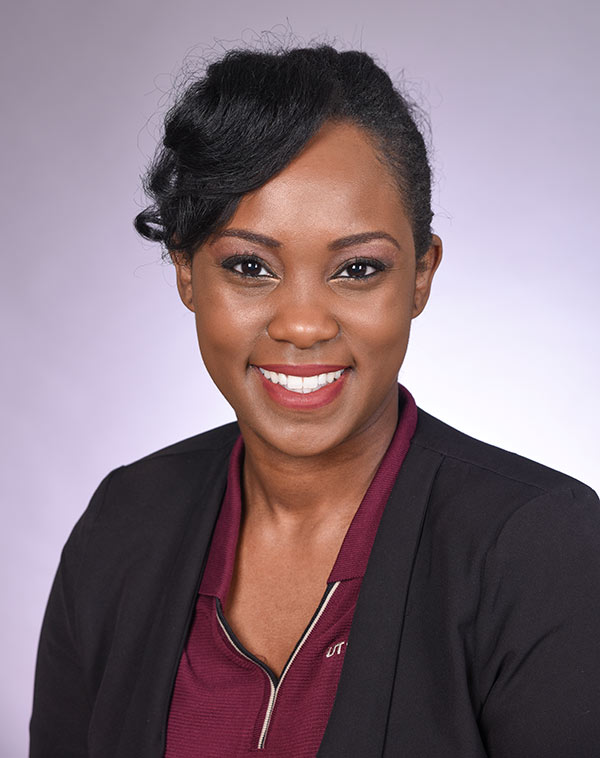 Woman with black hair, wearing black blazer over maroon shirt