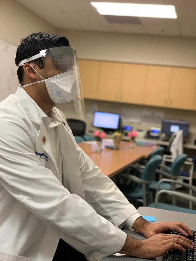 Man in white lab coat at a computer