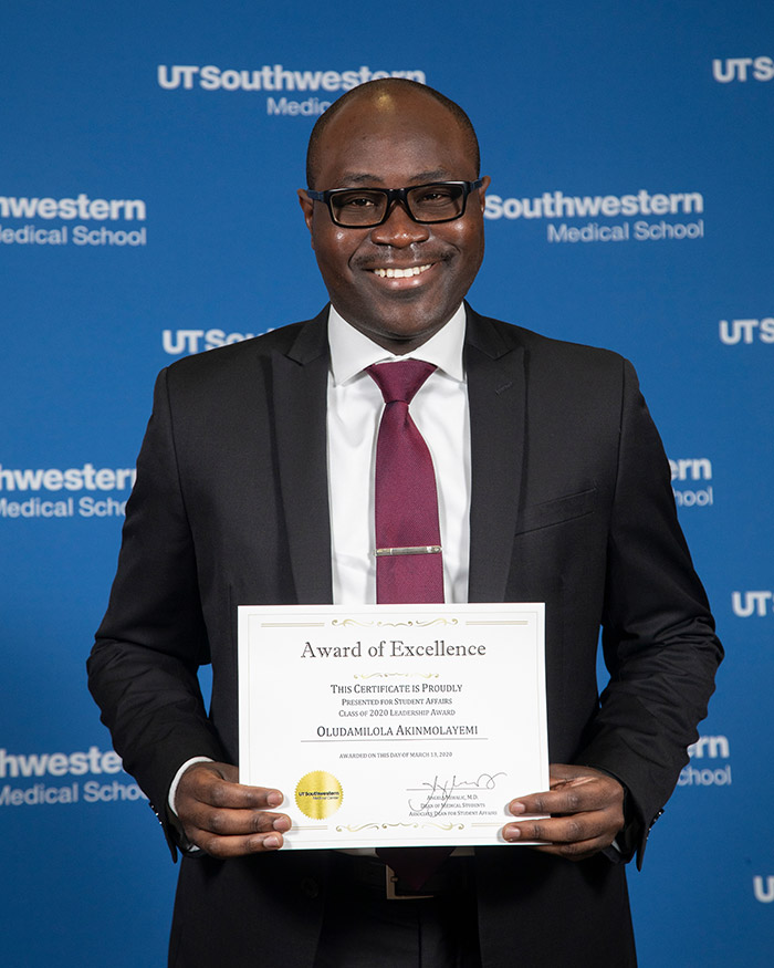 Manin black suit holding a certificate and smiling