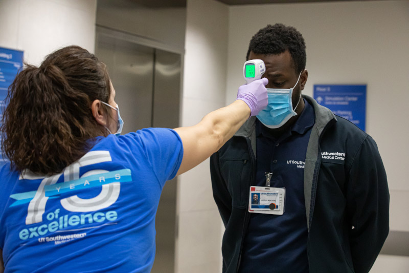 Woman using thermometer to check man's temperature on forehead