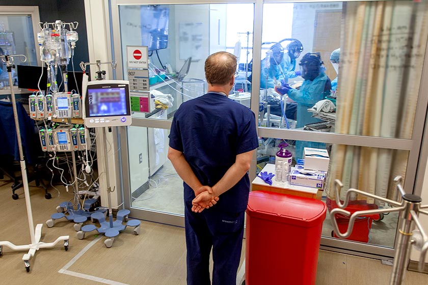 Man in scrubs standing outside of ICU room