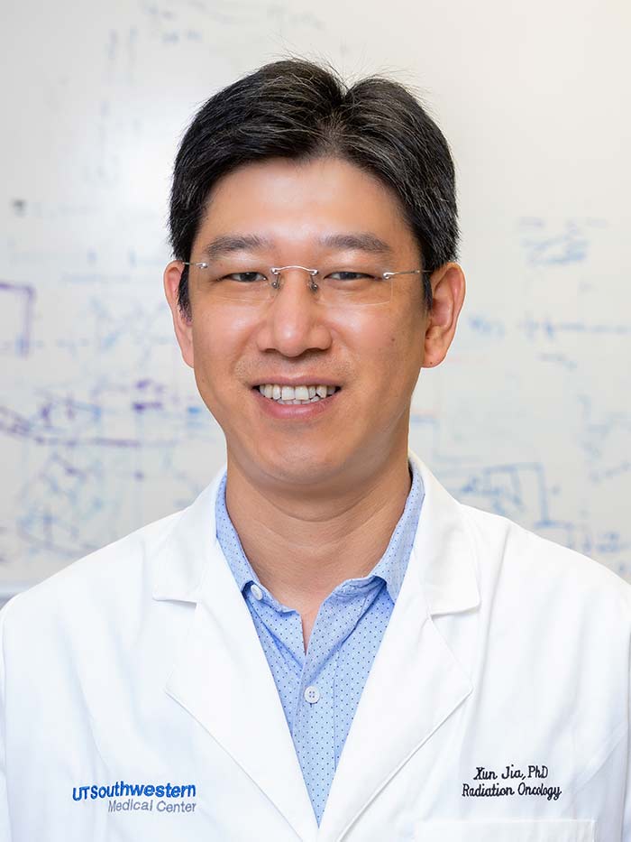 Man with short dark hair, frameless glasses, wearing white lab coat