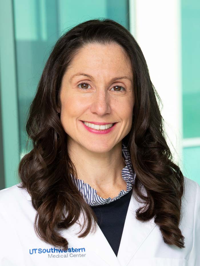 Woman with dark, long hair, wearing white lab coat