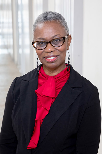 Woman with short grey hair, wearing black jacket and red shirt