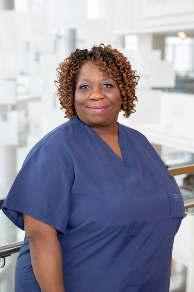 Woman with dark brown curls, wearing blue scrubs