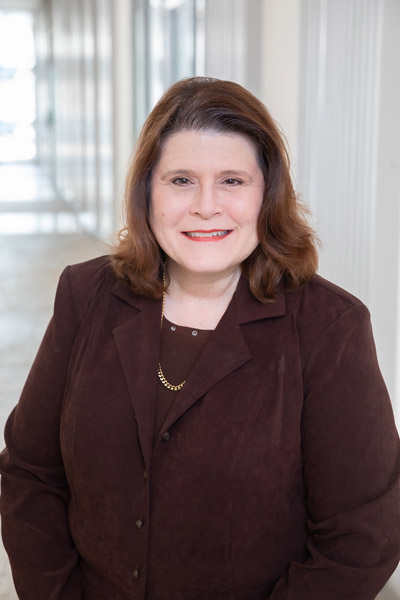 Woman with brown hair, wearing brown jacket