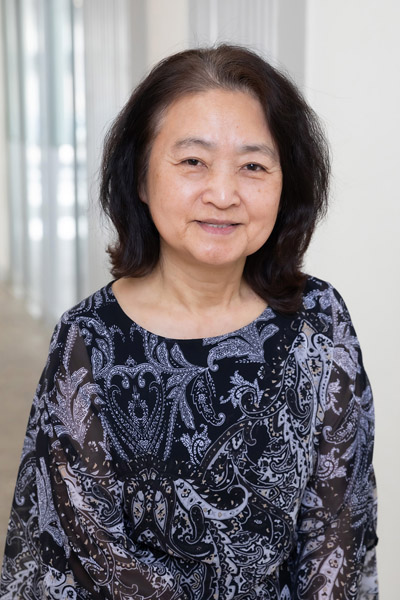 Woman with brown hair, wearing blue and black blouse