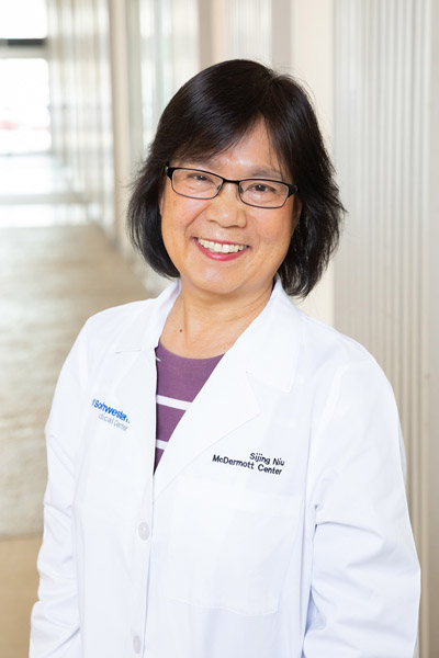 Woman with glasses, wearing lab coat