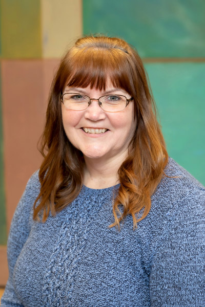 Woman with glasses, brown hair, and grey sweater