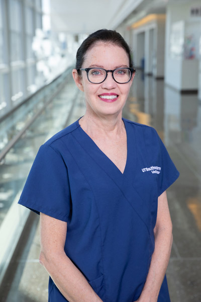 Woman with black hair, glasses, blue scrub top