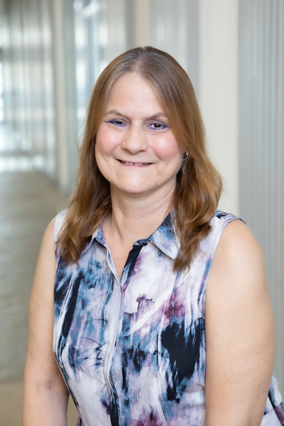 Woman with brown hair, with multi-colored top