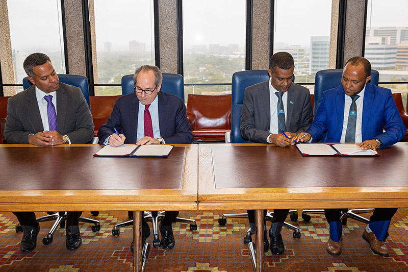 Group of four men sitting at a table signing papers