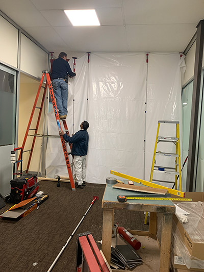 Man on ladder hanging plastic