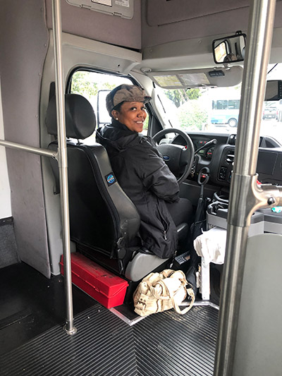 Woman sitting in bus driver seat smiling
