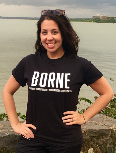 Woman standing by water, wearing black shirt that says BORNE