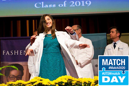 Woman donning on white lab coat on stage