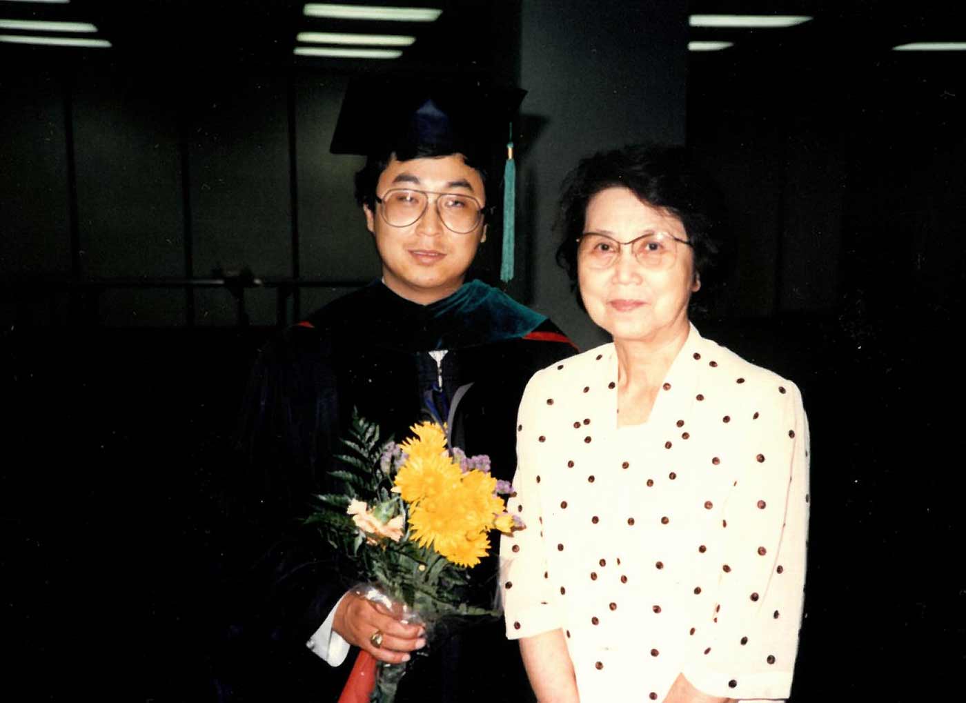 Man in graduation gown with woman in dotted dress