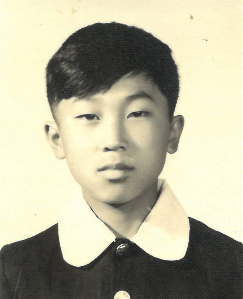 Young boy with short hair, wearing black shirt with white collar.