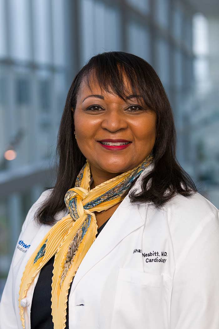 Woman with scarf, dark hair, wearing lab coat